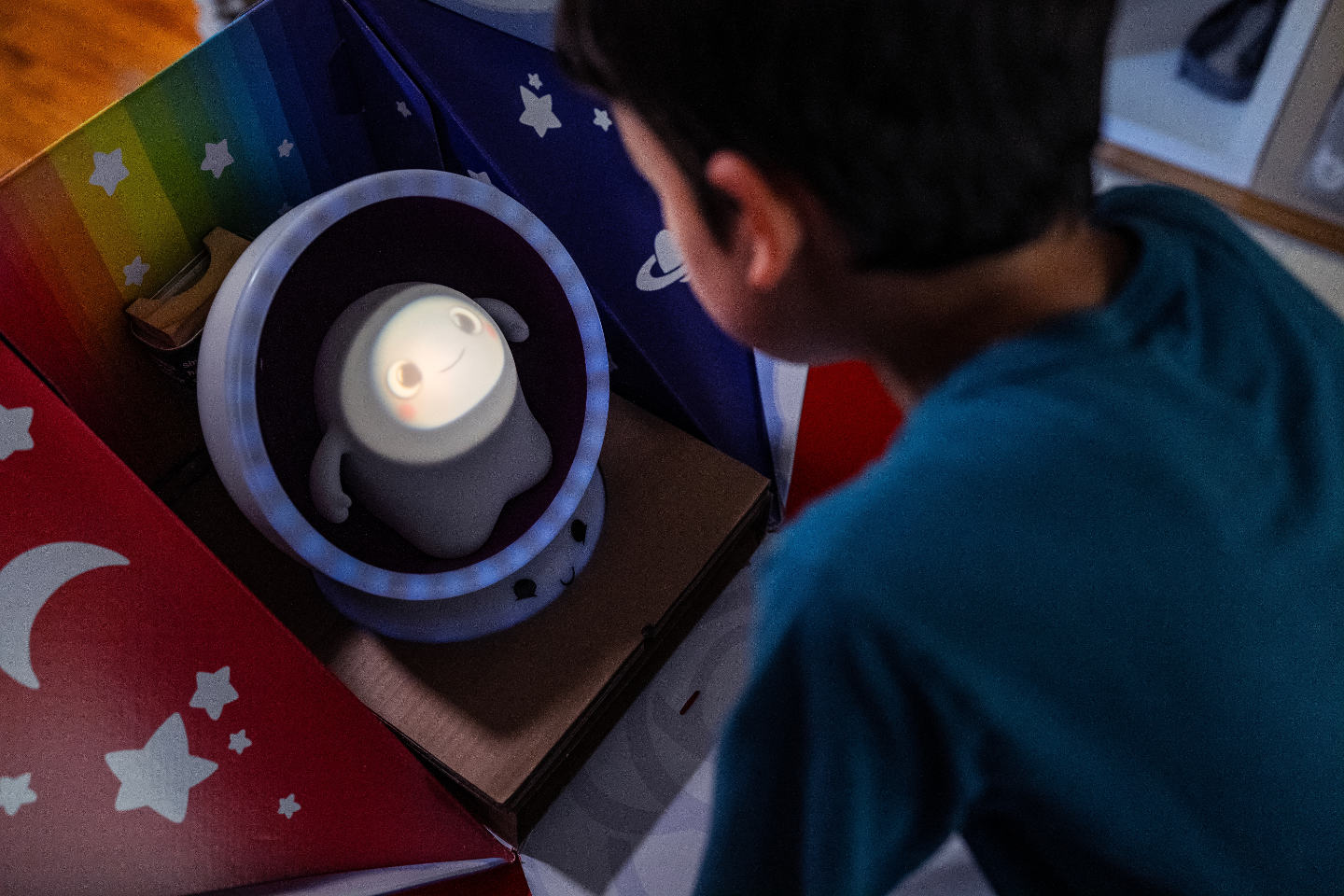 Image contains a photo of a child looking at Snorble®, a smart companion, sitting in their LullaPod®.