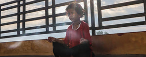 A child practicies meditation, a mindfulness activity, with the sun behind them.