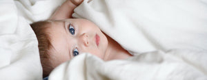 Image contains a photo of a small child in bed, and they could benefit from these sleep tips for children.